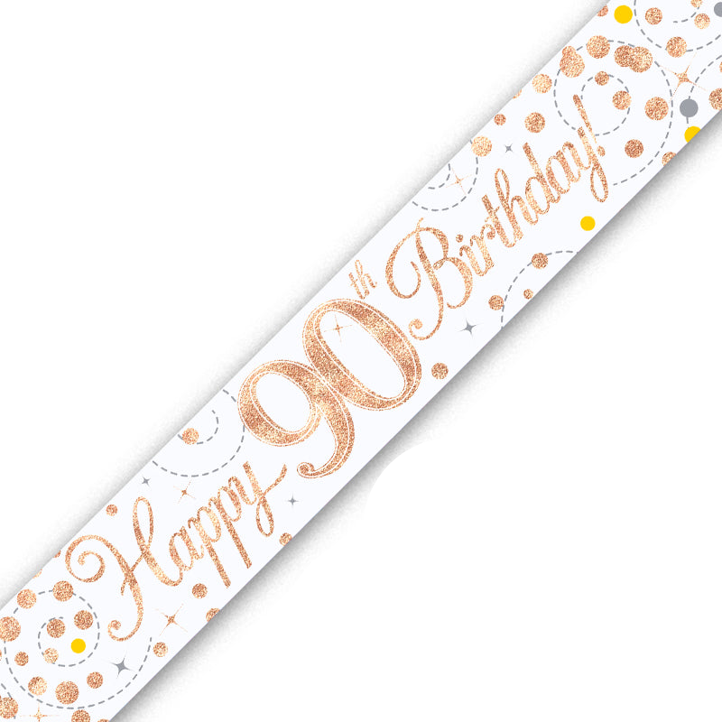 A diagonal white banner with 'Happy 90th Birthday!' in glittery rose gold script, decorated with matching rose gold and yellow confetti dots on a white background.