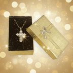 Gold cross necklace on a black cushion with an open gold box featuring a silver butterfly design.
