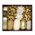 A gift decoration set in a rectangular box, featuring gold and white ribbons, gift bows, and thread spools on a white background.