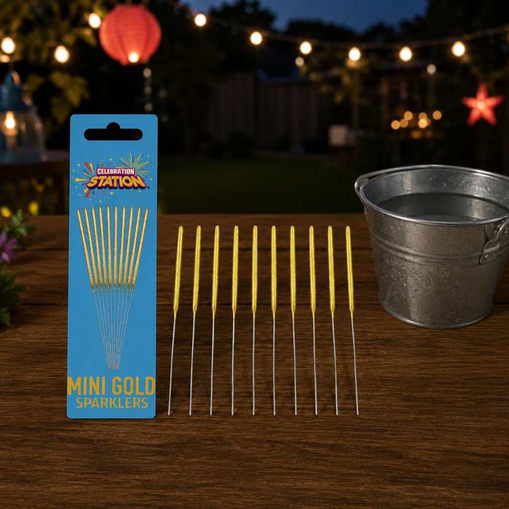 Ten unlit gold mini sparklers prepared outdoors beside a water bucket