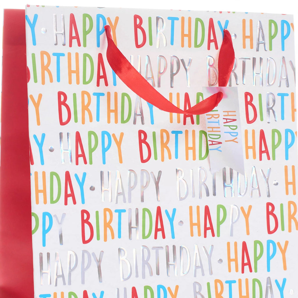 Close-up view of multi-coloured Happy Birthday print and ribbon carry handle on medium gift bag