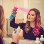 Woman applying Party Success fluorescent pink hair colour spray to her hair in front of a mirror