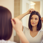 Woman clipping in a chocolate brown one-piece hair extension in a candid mirror moment