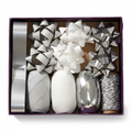 Silver bow and ribbon gift wrapping set in open plum box, studio white background