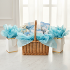 Premium gift hamper and gift bags overflowing with light blue tissue paper on white marble surface, celebration-ready styling