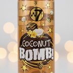 Extreme macro close-up of W7 Coconut Bomb Body Mist label showing Coconut Bomb graphic, gold star motifs, coconut illustration and amber liquid through clear bottle