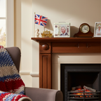 King Charles III money saving tin displayed on a mantelpiece with Union Jack flag and British royal memorabilia