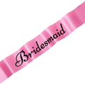 Pink satin bridesmaid sash with bold black writing, elegantly displayed on a blush marble surface with white rose petals
