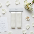 Flat lay of ivory wedding car ribbon and pull bows with white roses and wedding details on linen