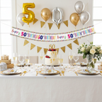 Elegant 50th birthday party table setting with multi-coloured foil banner displayed above