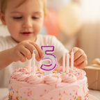Child's hands placing pink glitter number 5 birthday candle onto a birthday cake, warm bokeh background