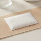Macro close-up of a tan Questaplast washproof plaster showing flexible fabric texture and absorbent wound pad