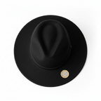Classic black fedora hat beside £1 coin on white background for instant size reference
