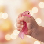 Child's hand squeezing a pink squishy sticky fish toy showing its soft squeezy gel texture