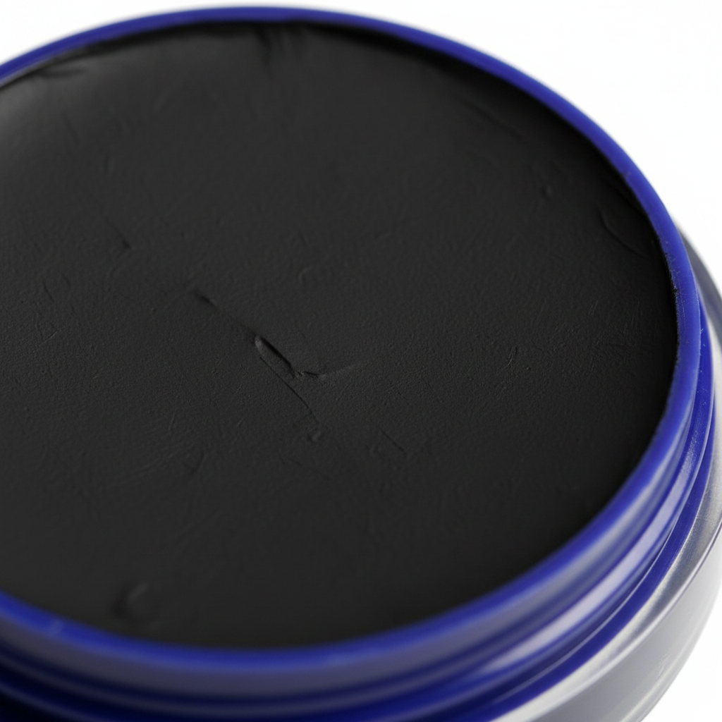 Extreme macro close-up of Snazaroo Classic Black Face Paint surface showing rich matte black pigment texture and cobalt blue rim detail