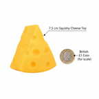 Large squishy triangle cheese toy 7.5cm beside a £1 coin showing scale, flat lay on white background