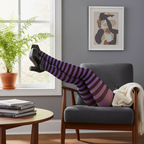 Womens legs in purple and black striped tights in a stylish living room setting with natural window light