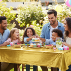 Gold table cover on an outdoor garden party table with family celebrating in the sunshine