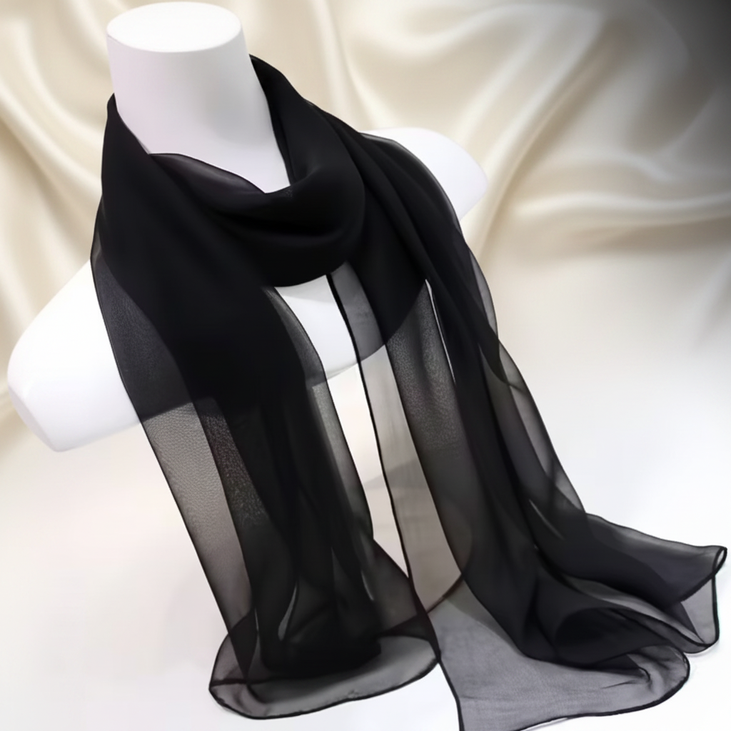 Womens long lightweight solid black chiffon scarf draped on mannequin against luxury cream and charcoal studio background