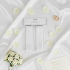 Flat lay of white wedding car ribbon and pull bows with roses, rings and wedding invitation on silk