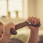Child's hand squeezing and stretching a brown Squeezy Poop squishy stress toy showing elasticity