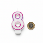 Pink Number 8 Birthday Candle flat lay beside a £1 coin for size reference on white background