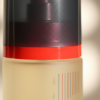 Extreme macro close-up of Taylor of London Chique cologne bottle showing red accent ring, charcoal grey cap texture and cream bottle detail