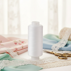 Premium white cotton sewing thread reel 500 yards displayed on elegant sewing workspace with fabric swatches and vintage scissors