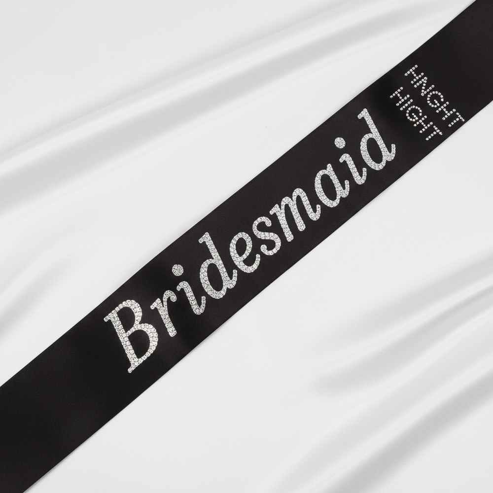 Black satin and diamante bridesmaid sash displayed on white background showing luxurious satin finish and sparkling crystal detailing