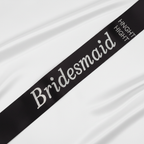 Black satin and diamante bridesmaid sash displayed on white background showing luxurious satin finish and sparkling crystal detailing