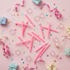 Flat lay of pink party candles with confetti and gift boxes on a pastel pink surface