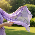 Close-up of hands holding flowing purple chiffon botanical leaf scarf in lush garden setting - detail lifestyle photo
