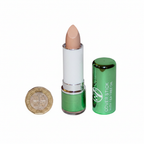 W7 Tea Tree Concealer Stick Light/Medium flat lay beside £1 coin for size reference, white background with soft overhead lighting showing metallic green casing and light peachy-beige bullet