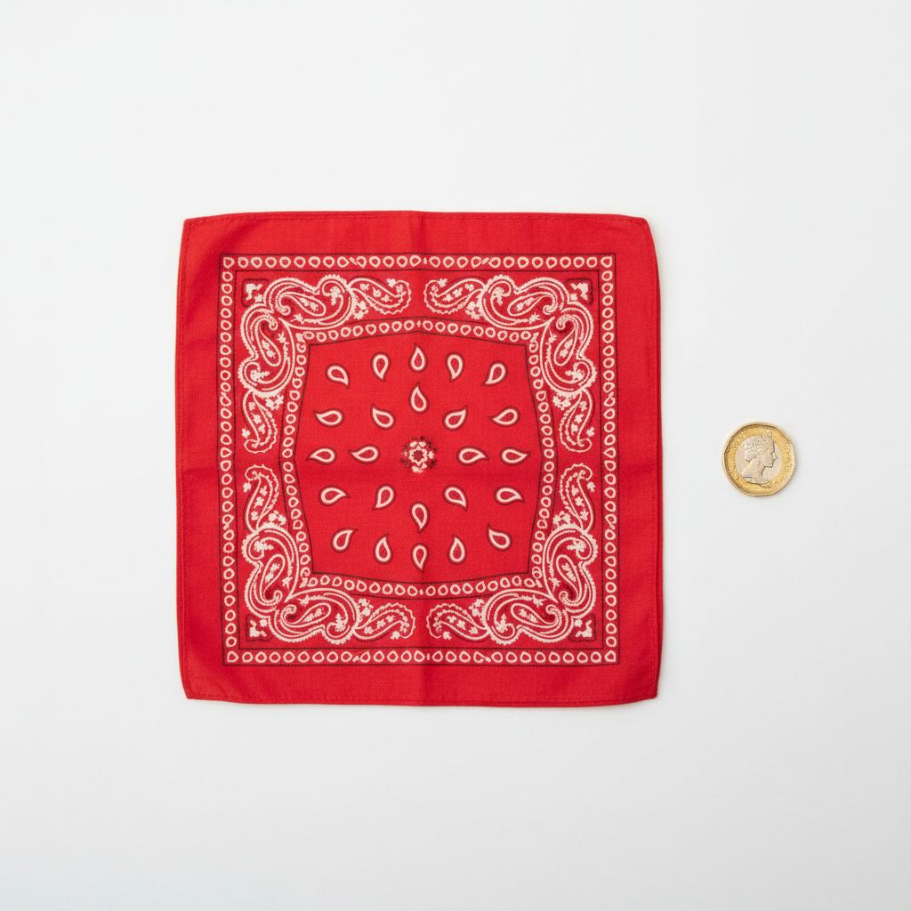 Red and white paisley bandana flat lay on white background with pound coin for scale reference