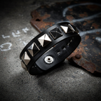 Black leather wristband with silver pyramid studs on edgy background