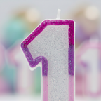 Extreme macro close-up of pink glitter border texture on number 1 birthday candle showing sparkle craftsmanship