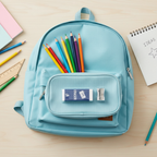 Flat lay of pencil sharpener and eraser set inside an open pencil case surrounded by coloured pencils, ruler and notebook on a wooden desk