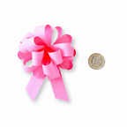 Large light pink pull bow 6 inch placed beside a £1 coin on white background to show scale