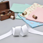 Soft white elastic band displayed on fabric swatches and sewing notions background