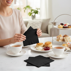 Black luncheon napkins at a cosy home afternoon tea with teacups and cake stand