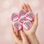 Close-up of manicured hands fanning out all 6 Hen Night Bachelorette Badges showing the fun playful designs