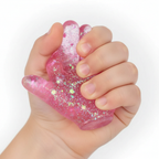 Close-up of child's hand squeezing the fingers of a pink Stretch and Squeeze Hand Gel Toy showing glitter gel shifting inside