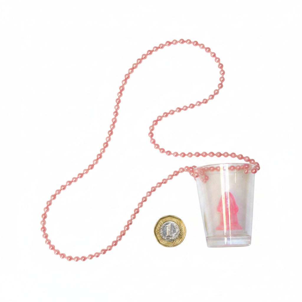 Flat lay of pink bead necklace with willy shot glass pendant on white background beside a £1 coin showing product size