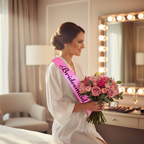 Bridesmaid wearing a pink satin sash with black writing over a white robe getting ready in a luxury bridal suite
