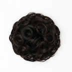 Extreme macro close-up of dark brown curly hair bun showing individual curl texture, warm espresso undertones and strand craftsmanship detail