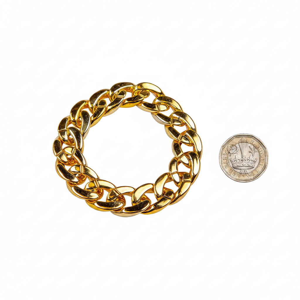 Chunky gold bracelet beside a £1 coin on white background showing product size — flat lay