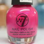 Extreme macro close-up of W7 Fluorescent Pink Nail Polish bottle showing vivid fluorescent hot pink polish intensity and W7 branding detail through clear glass