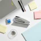 Flat lay of desktop stapler with 1000 staples and office stationery on white desk