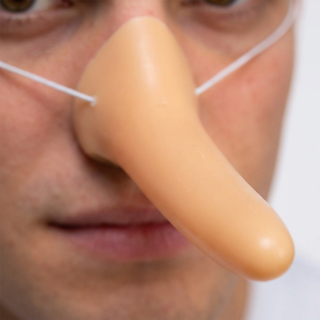 Close-up of the peach Funny Long Nose Liar rounded tip and white elastic worn on a man's face