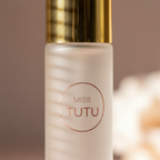 Extreme macro close-up of Miss Tutu frosted glass bottle texture and metallic gold cap — showcasing premium material quality